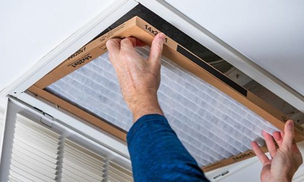 Person installing an HVAC air filter.