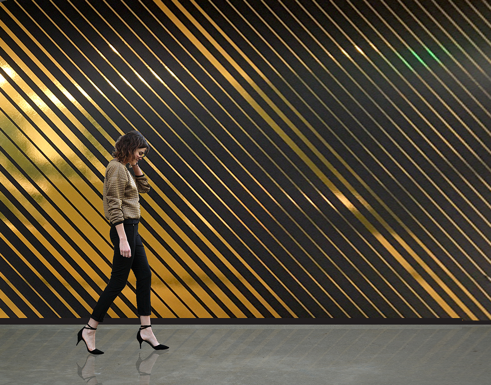 Women walking in front of a black wall with various thickness of reflective gold stripes angled on top