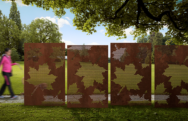 Person walking behind four large brown metal panels with big leaves cut out of them sitting in the grass besides the sidewalk.