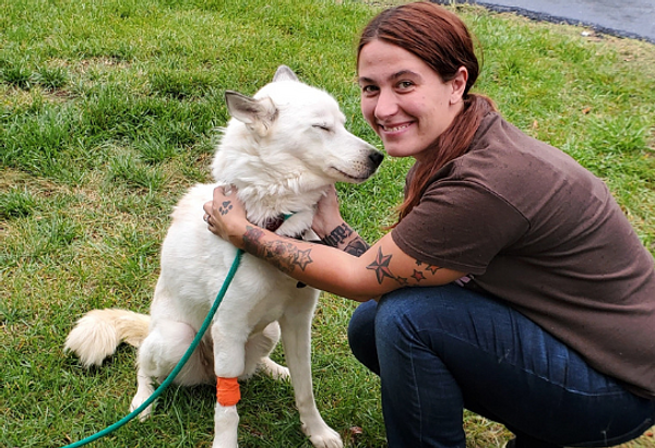 A woman pets Roxy the white dog