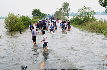 Thai villagers walk down flooded roadway