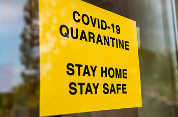 Sign in store window: "COVID-19 Quarantine. Stay Hone. Stay Safe"