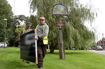 Workers carry a solar panel to be installed on the roof of Balcombe primary school, as part of a community-owned renewable energy project