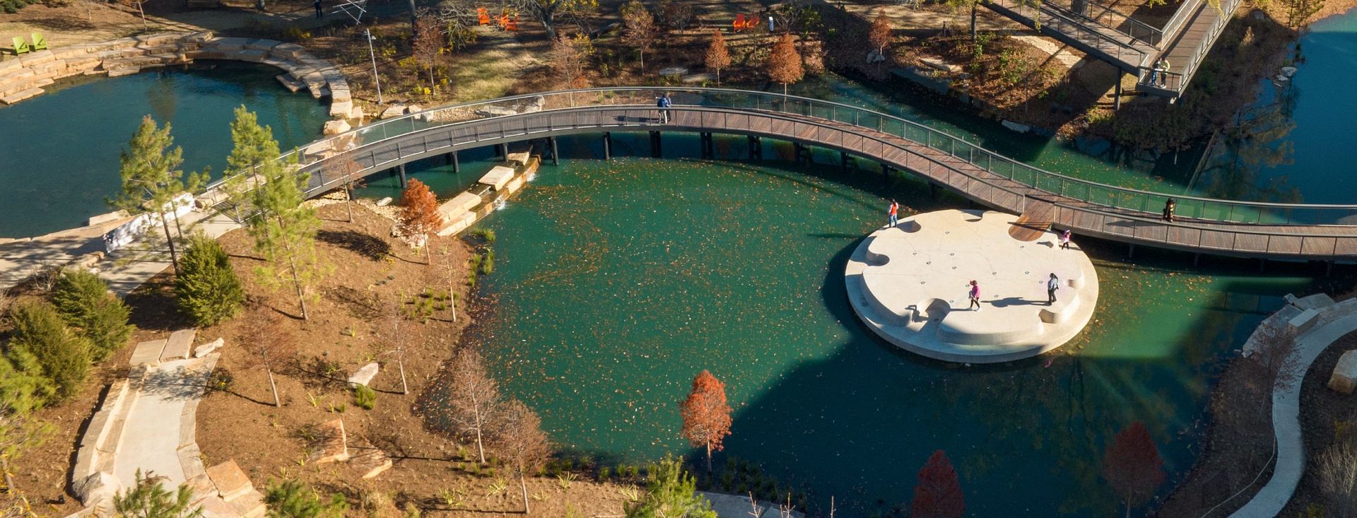 A pond with a bridge crossing it from above.