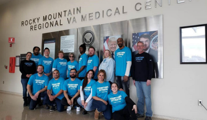 A group of 17 people pose for a photo outside of a sign for the Rocky Mountain Regional VA Medical Center