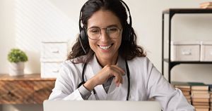 Happy friendly female physician in headphones chatting to patient