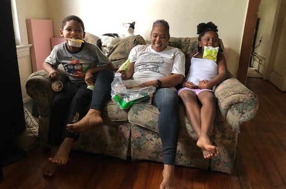 Client Asia sitting on the couch with her two grandkids. They are holding meal components