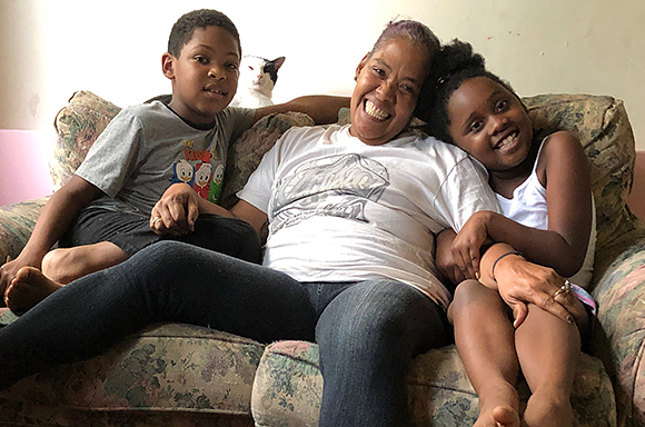 Client Asia sitting on the couch with her grandchildren and cat