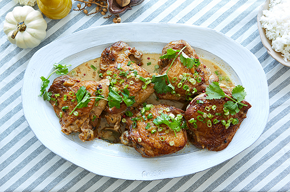 Adobo-Braised turkey thighs with scallions on a white plate