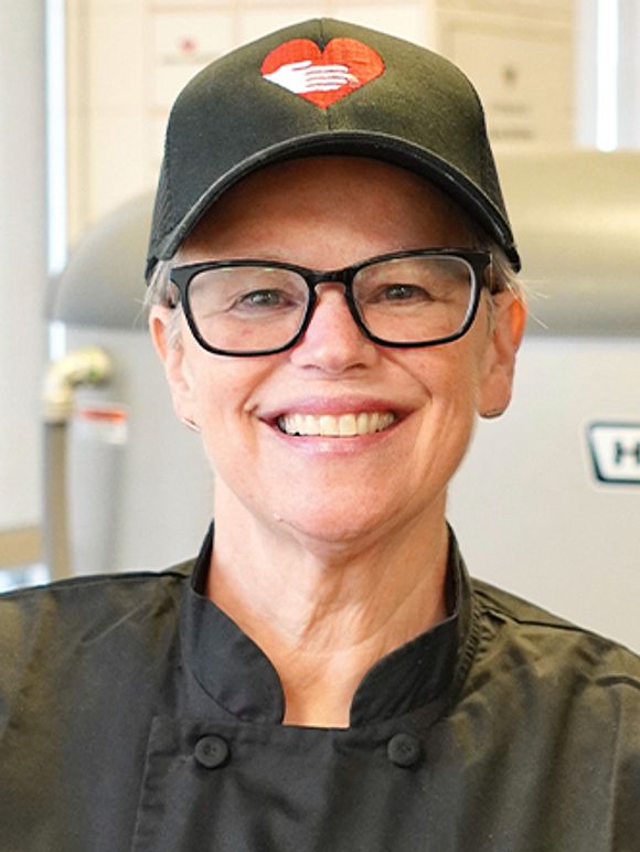 A headshot photo of Chef Dorothy wearing a God's Love hat.