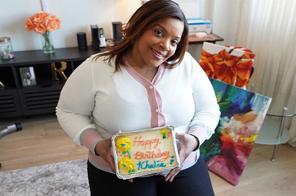 A photo of client, Khalia, smiling and holding a birthday cake.