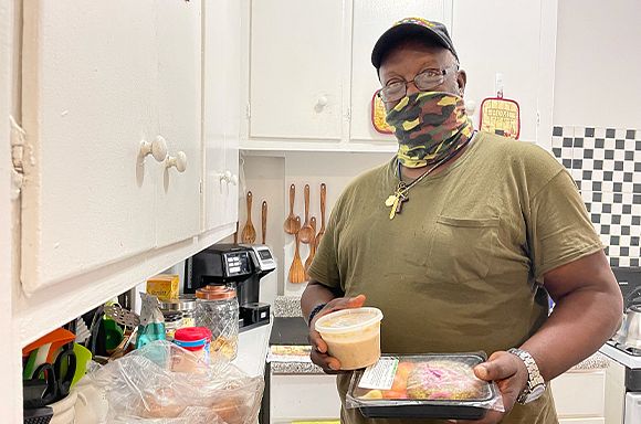 A photo of client, Raphael, holding meals in his kitchen.