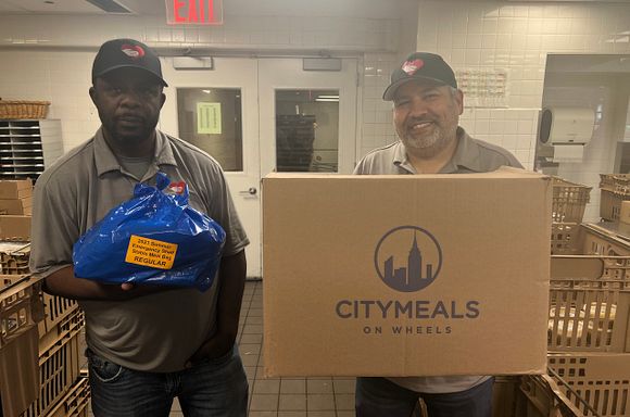 A photo of two God's Love We Deliver staff members holding shelf-stable meals from Citymeals.