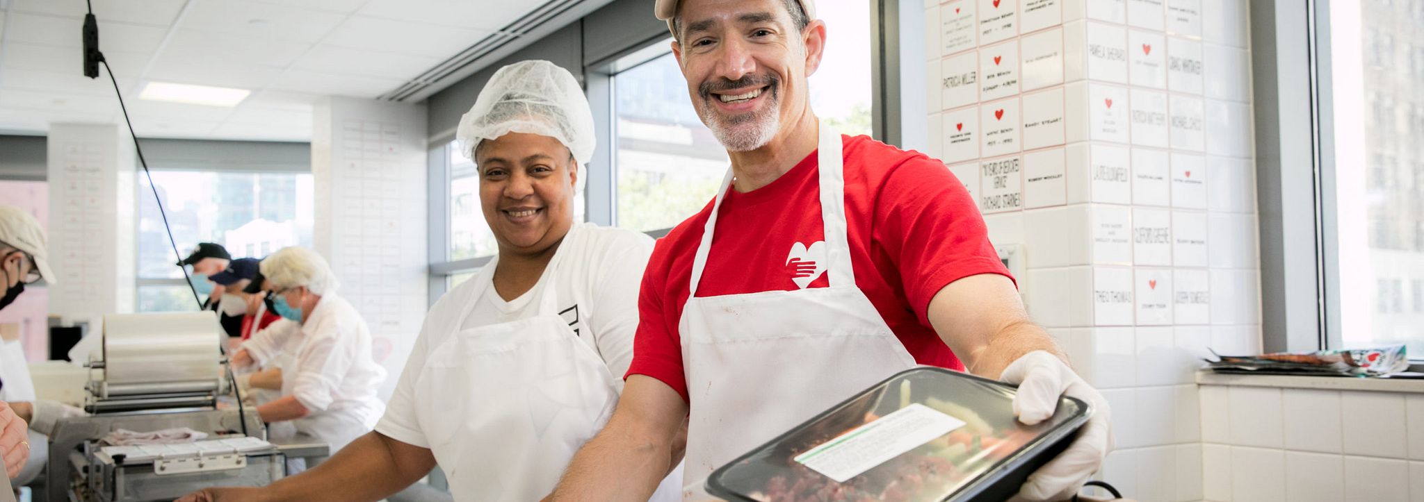 A photo of two volunteers smiling at the camera in the God's Love kitchen.