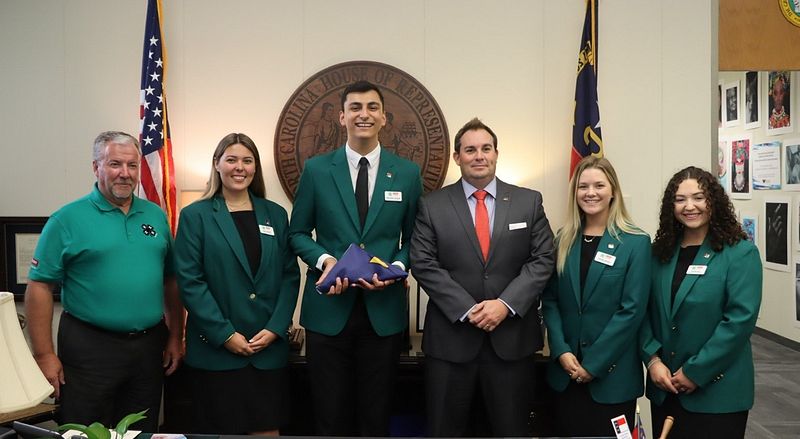 The planning team of the 4-H Citizenship Focus conference stand with Dr. Mike Yoder and Majority Leader John Bell while receiving a state flag for their dedication to the 4-H mission.