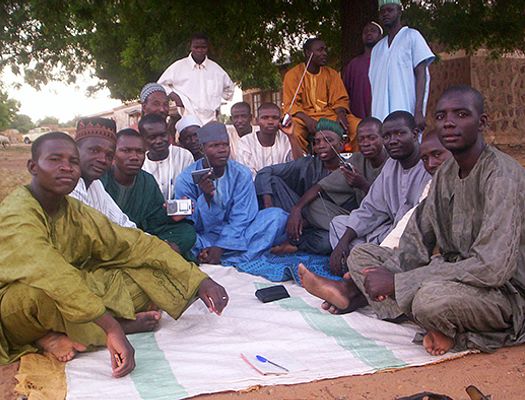 A group of Nigerian men sit together while listening to the radio