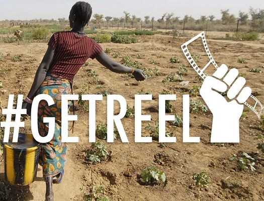 A woman carrying water through a dirt field with #GETREEL overlaid on the photo