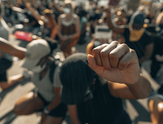 A group of Black Lives Matter protestors kneel with their fists up in the air