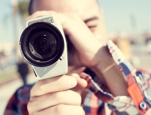 A man holds up a camera up to his face to take a picture
