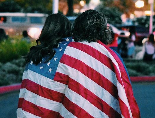 Two women wear an American flag over their shoulders