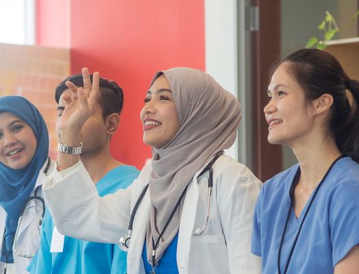 A female doctor raises her hand from a line of other healthcare workers