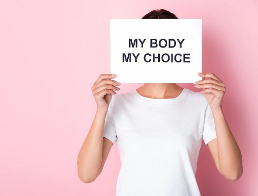 A woman holding up a sign over her face that says "MY BODY MY CHOICE"