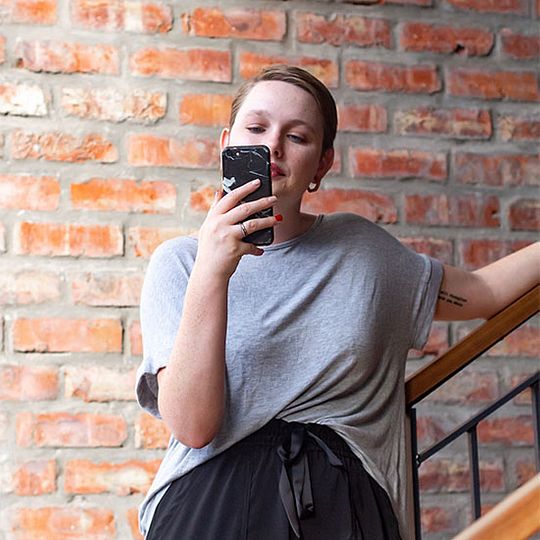 Woman stands on staircase staring at her mobile device