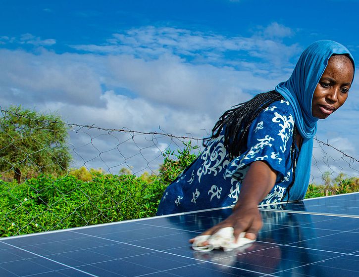 Woman wiping down a ground mount solar panel