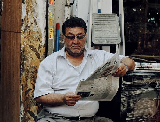 a man sits while reading a newspaper
