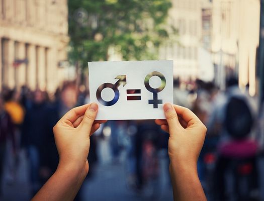 A paper sign that says women are equal to men