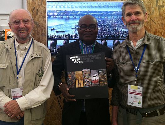 Three men pose with OVER book at COP21
