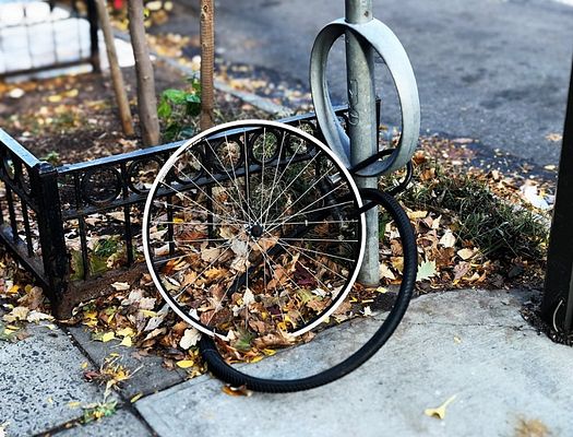 a broken bicycle wheel locked to a bike stand