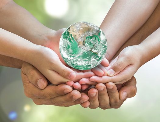 A young and old person together hold a small globe