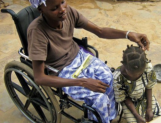 Ténimba, sitting in a wheelchair, and her daughter, who sits on the floor