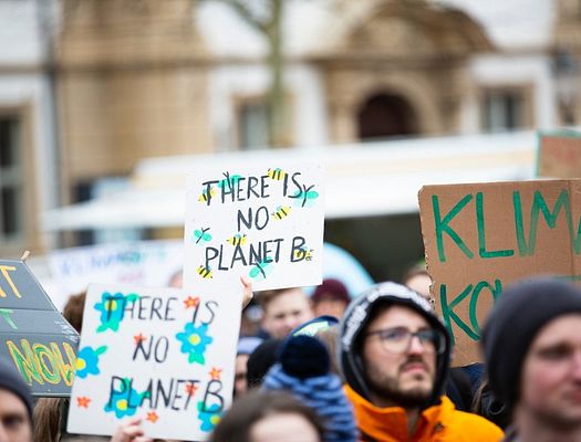 A group of climate change protesters. A sign in the foreground says "There is no Planet B"