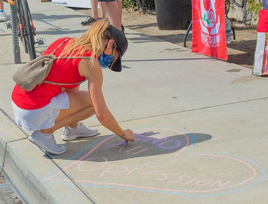 A woman draws with chalk on the sidewalk