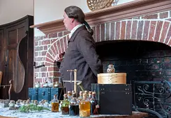 Man dressed in colonial attire with table of colonial medicines and tinctures