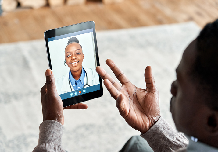 Over should view of African American patient video calling virtual doctor on tablet.